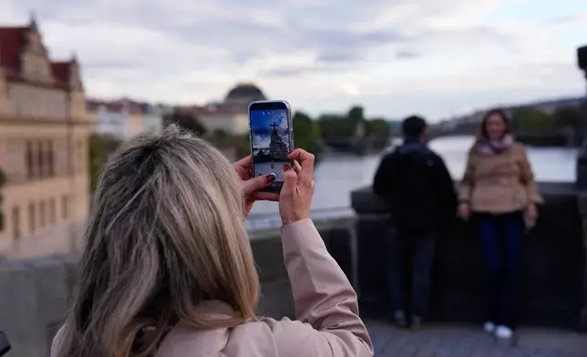 People pose to recreate a famous photo of two members of Depeche Mode, taken by Dutch photographer Anton Corbijn in 1988, by the Pieta statue at the Charles Bridge in Prague, Czech Republic, Thursday, Sept. 24, 2026. (AP Photo/Petr David Josek)