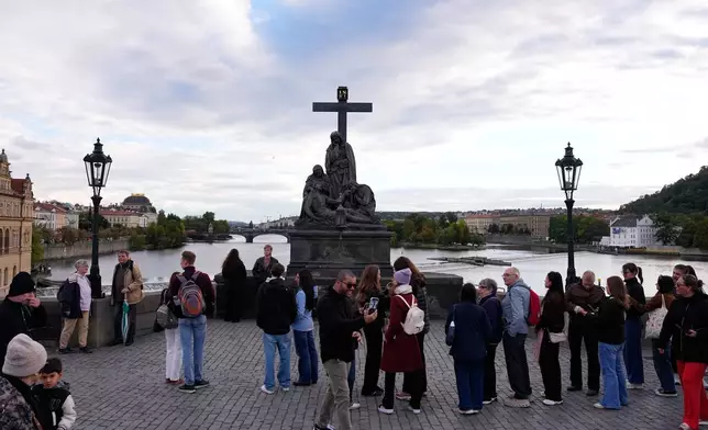 People wait in line to recreate a famous photo of two members of Depeche Mode, taken by Dutch photographer Anton Corbijn in 1988, by the Pieta statue at the Charles Bridge in Prague, Czech Republic, Thursday, Sept. 24, 2026. (AP Photo/Petr David Josek)