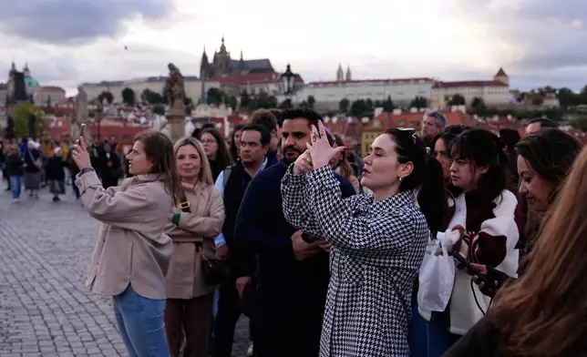 People wait in line to recreate a famous photo of two members of Depeche Mode, taken by Dutch photographer Anton Corbijn in 1988, by the Pieta statue at the Charles Bridge in Prague, Czech Republic, Thursday, Sept. 24, 2026. (AP Photo/Petr David Josek)