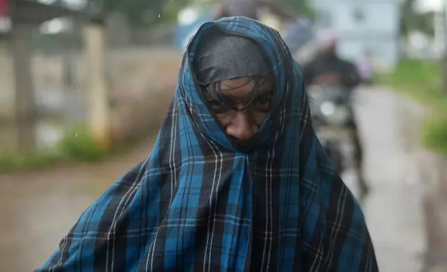 A man shields himself from the rain in Kakinada, India, as Cyclone Arnab crossed the Andhra Pradesh coast early Wednesday, Oct. 28, 2026. (AP Photo/Mahesh Kumar A.)