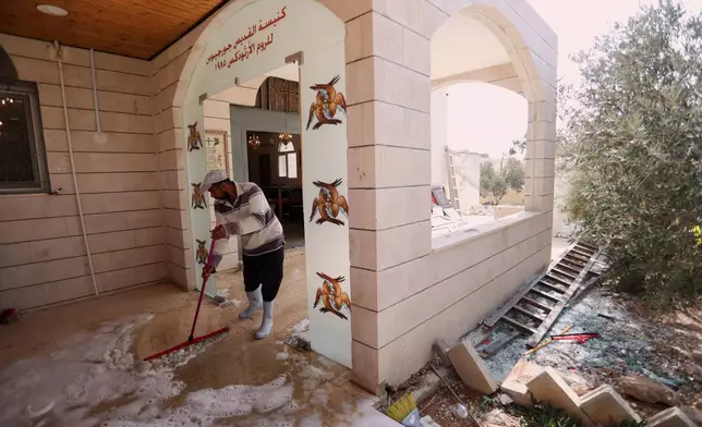 A worker scrubs the floor of St. George's Greek Orthodox Church a day after gunmen opened fire during a funeral in the village of Hamoud, in Jordan's Karak governorate, Saturday, Oct. 24, 2026. (AP Photo/Raad Adayleh)