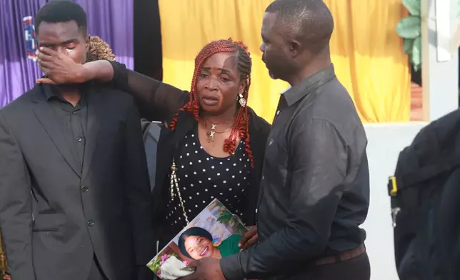 Anushuni Courage Abombi,left, the 18-year-old son of Achiah Geraldine, a woman who was murdered, is comforted by relatives outside a mortuary chapel in Yaoundé, Cameroon, Friday, Sept. 18, 2026. (AP Photo/Angel Ngwe)