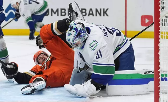 Anaheim Ducks left wing Alex Killorn, left, collides with Vancouver Canucks goaltender Leevi Meriläinen during overtime in an NHL hockey game Tuesday, Oct. 27, 2026, in Anaheim, Calif. (AP Photo/Gregory Bull)