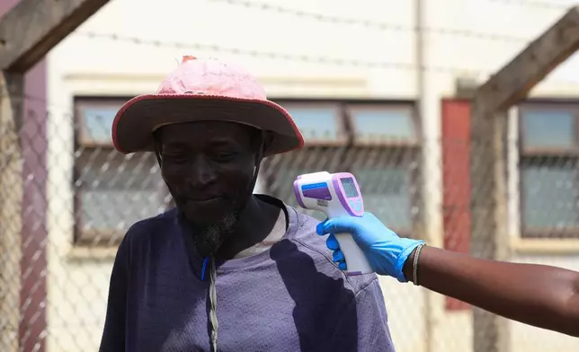 A Kenyan health worker checks the temperatures of travelers crossing from Uganda to Kenya as part of measures to contain the spread of Ebola virus, in Busia, Kenya, Thursday, Oct. 15, 2026. (AP Photo/Andrew Kasuku)