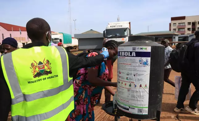 People disinfect their hands as a Kenyan health worker checks the temperatures of travelers crossing from Uganda to Kenya as part of measures to contain the spread of Ebola virus, in Busia, Kenya, Thursday, Oct. 15, 2026. (AP Photo/Andrew Kasuku)