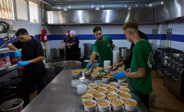 Employees and migrant volunteers prepare meals for migrants at the Luna Blanca NGO's headquarters in Ceuta, Wednesday, Sept. 30, 2026. (AP Photo/Bernat Armangue)