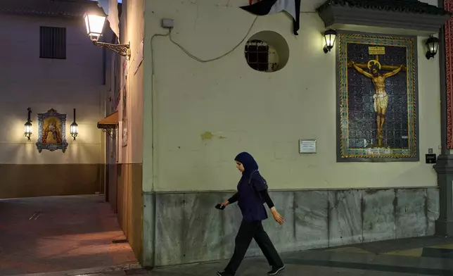 A Muslim woman walks past a Catholic church in downtown Ceuta, Thursday, Oct. 1, 2026. (AP Photo/Bernat Armangue)
