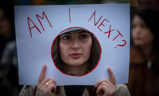 A woman holds a sign "Am I Next" as thousands of people gather in Kosovo's capital to protest the killing of a Kosovo-American woman, Arlinda Zekaj, whose death sparked public outrage and renewed calls for accountability over violence against women in capital Pristina, Kosovo, on Wednesday, Oct.28, 2026. (AP Photo/Visar Kryeziu)