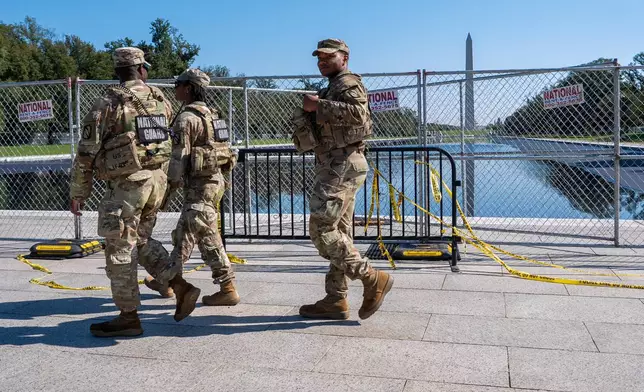 Members of the National Guard walk past the Lincoln Memorial Reflecting Pool, where some water can be seen, Tuesday, Oct. 13, 2026, in Washington. (AP Photo/Jacquelyn Martin)