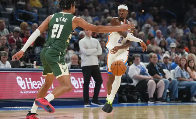 Oklahoma City Thunder guard Shai Gilgeous-Alexander (2) passes around Milwaukee Bucks forward Ousmane Dieng (21) during the first half of an NBA basketball game, Wednesday, Oct. 7, 2026, in Oklahoma City. (AP Photo/Kyle Phillips)