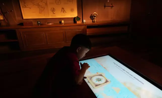 A visitor watches an interactive screen inside the full-scale reproduction of the 17th century Spanish galleon called Espiritu Santo at the Museo del Galeon in Manila, Philippines on Friday, Aug. 28, 2026. (AP Photo/Aaron Favila)