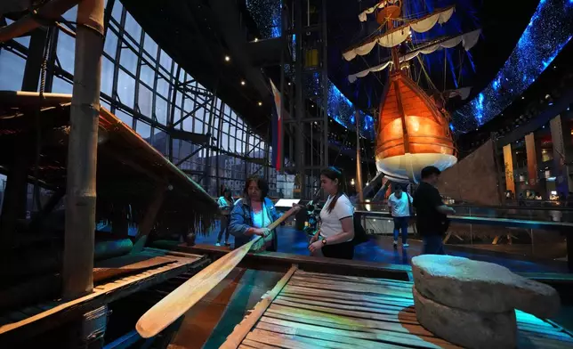Visitors look at an oar of a balangay, an ancient Filipino wooden boat, beside the Espiritu Santo galleon at the Museo del Galeon in Manila, Philippines on Friday, Aug. 28, 2026. (AP Photo/Aaron Favila)