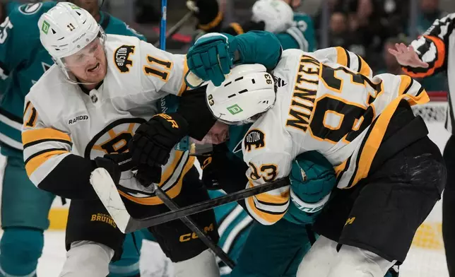 San Jose Sharks defenseman Jacob Trouba, middle, fights Boston Bruins center Casey Mittelstadt (11) and center Fraser Minten (93) during the second period of an NHL hockey game, Tuesday, Oct. 13, 2026, San Jose, Calif. (AP Photo/Jeff Chiu)