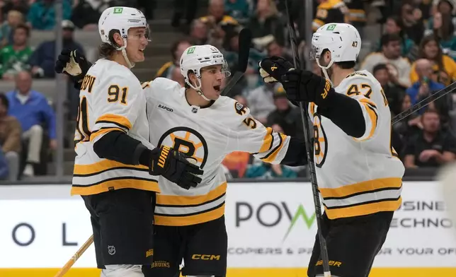 Boston Bruins center Matthew Poitras, middle, is congratulated by defenseman Nikita Zadorov (91) and center Mark Kastelic (47) after scoring against the San Jose Sharks during the second period of an NHL hockey game, Tuesday, Oct. 13, 2026, San Jose, Calif. (AP Photo/Jeff Chiu)