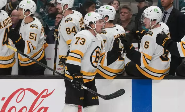 Boston Bruins defenseman Charlie McAvoy (73) is congratulated by teammates after scoring during the first period of an NHL hockey game, Tuesday, Oct. 13, 2026, San Jose, Calif. (AP Photo/Jeff Chiu)