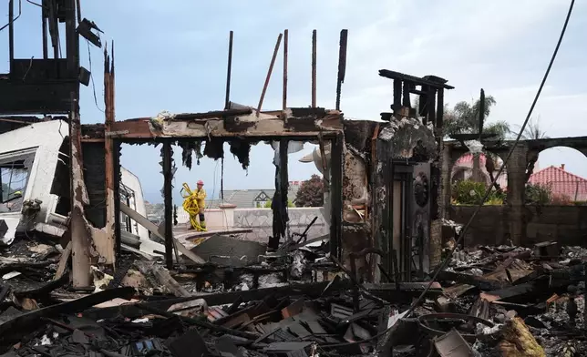Firefighters gather hose among a destroyed home after the Norte Fire Saturday, Oct. 17, 2026, in San Juan Capistrano, Calif. (AP Photo/Gregory Bull)