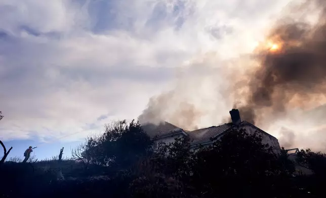 A firefighters works to put out a fire on a house engulfed in flames during the Norte Fire on Friday, Oct. 16, 2026, in San Juan Capistrano, Calif. (AP Photo/Jae C. Hong)