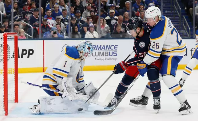 Buffalo Sabres' Ukko-Pekka Luukkonen, left, makes a save against Columbus Blue Jackets' Danton Heinen, center, as Sabres' Rasmus Dahlin (26) defends during the second period of an NHL hockey game, Thursday, Oct. 1, 2026, in Columbus, Ohio. (AP Photo/Jay LaPrete)