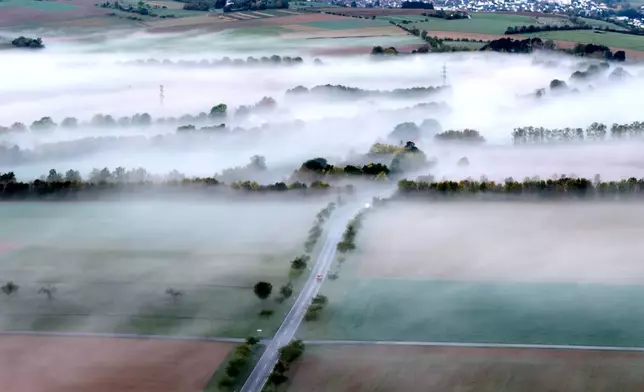 A car drives through a foggy landscape in the Taunus region near Frankfurt, Germany, Wednesday, Oct. 14, 2026. (AP Photo/Michael Probst)