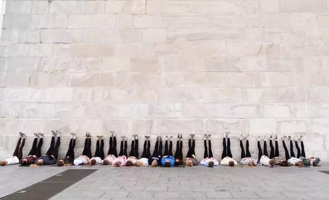 Eighth graders from Kalida Local Schools in Kalida, Ohio take a photo with their feet up, leaning on the Washington Monument, Friday, Oct. 16, 2026, in Washington. (AP Photo/Manuel Balce Ceneta)