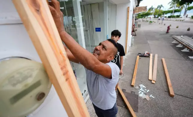 A man boards up a shop as Hurricane Simon approaches Puerto Vallarta, Mexico, Saturday, Oct. 10, 2026. (AP Photo/Fernando Llano)