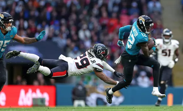 Jacksonville Jaguars wide receiver Travis Hunter (12) gets away from Houston Texans safety M.J. Stewart (29) during an NFL football game in London, Sunday, Oct. 18, 2026. (AP Photo/Ian Walton)
