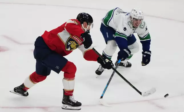 Florida Panthers left wing Brady Tkachuk, left, scores the game winning goal past Vancouver Canucks defenseman Zeev Buium, right, during overtime in an NHL hockey game, Thursday, Oct. 15, 2026, in Sunrise, Fla. (AP Photo/Lynne Sladky)
