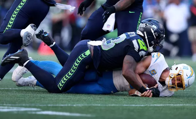 Los Angeles Chargers quarterback Justin Herbert (10) is tackled by Seattle Seahawks linebacker Ernest Jones IV (13) during the second half of an NFL football game, Sunday, Oct. 4, 2026, in Seattle. (AP Photo/Kevin Ng)
