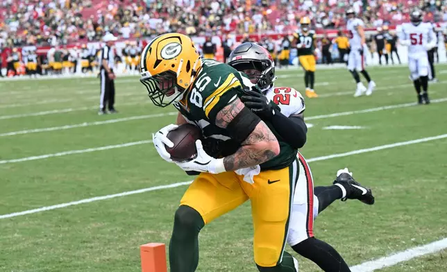 Green Bay Packers tight end Tucker Kraft (85) makes a catch for a touchdown as Tampa Bay Buccaneers safety Tykee Smith (23) defends during the second half of an NFL football game against the Tampa Bay Buccaneers in Tampa, Fla., Wednesday, Sept. 30, 2026. (AP Photo/Jason Behnken)