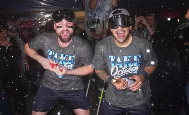 Tampa Bay Rays' Ryan Vilade, left, and Victor Mesa Jr., center right, celebrate in the locker room after the team's win in Game 3 of baseball's American League Division Series against the New York Yankees, Wednesday, Oct. 7, 2026, in New York. (AP Photo/Seth Wenig)