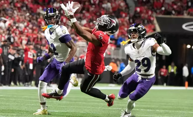 Atlanta Falcons wide receiver Jahan Dotson, center, catches a pass between Baltimore Ravens cornerback Nate Wiggins (2) and cornerback Chandler Rivers (29) during the first half of an NFL football game, Sunday, Oct. 11, 2026, in Atlanta. (AP Photo/Mike Stewart)