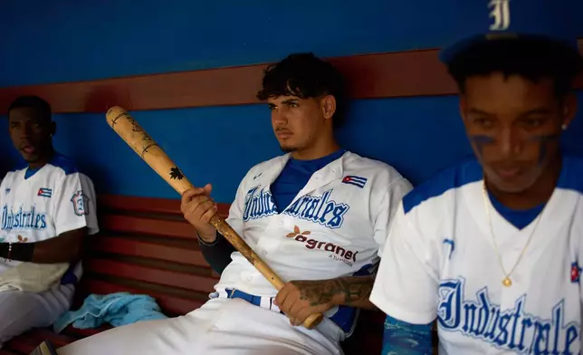 An Industriales player, wearing a jersey featuring a private sponsor logo, holds a baseball bat before a game against Pinar del Río in Havana, Cuba, Wednesday, Oct. 7, 2026. (AP Photo/Ramon Espinosa)