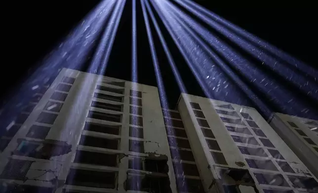 Lights are raised among buildings to honor the victims of two catastrophic earthquakes in June, 100 days after the disaster in La Guaira, Venezuela, Friday, Oct. 2, 2026. (AP Photo/Ariana Cubillos)