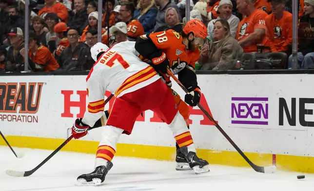 Calgary Flames defenseman Kevin Bahl (7) checks Anaheim Ducks left wing A.J. Greer (18) during the second period of an NHL hockey game, Tuesday, Oct. 13, 2026, in Anaheim, Calif. (AP Photo/Kyusung Gong)