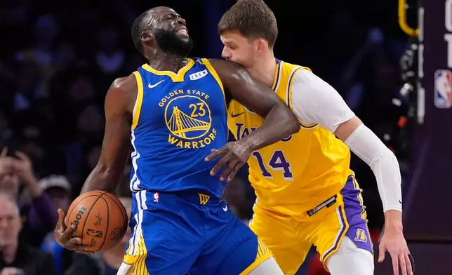 Los Angeles Lakers center Walker Kessler, right, is hit in the face by Golden State Warriors forward/center Draymond Green as he tries to defend during the first half of an NBA basketball game Wednesday, Oct. 21, 2026, in Los Angeles. (AP Photo/Mark J. Terrill)