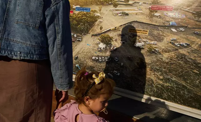 A person's shadow is cast on a large photo of the site of the Nova music festival, taken after hundreds of revelers were killed and abducted there three years prior in the Oct. 7 Hamas attack, on display at the site of the attack near Kibbutz Reim in southern Israel, Friday, Oct. 2, 2026. (AP Photo/Oded Balilty)