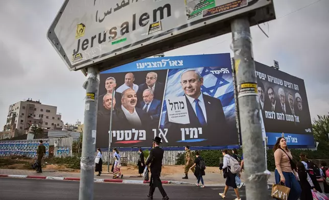 People walk past a Likud party campaign billboard featuring Israeli Prime Minister Benjamin Netanyahu alongside opposition party leaders and bearing the Hebrew slogan "Right or Palestine," ahead of Israel's general election, in Beni Brak, Israel, Sunday, Oct. 25, 2026. (AP Photo/Oded Balilty)