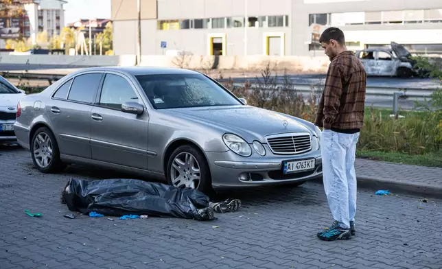 A man looks at a body of a man killed in a Russian strike on Chabany, near Kyiv, Ukraine, Tuesday, Oct. 20, 2026. (AP Photo/Dan Bashakov)