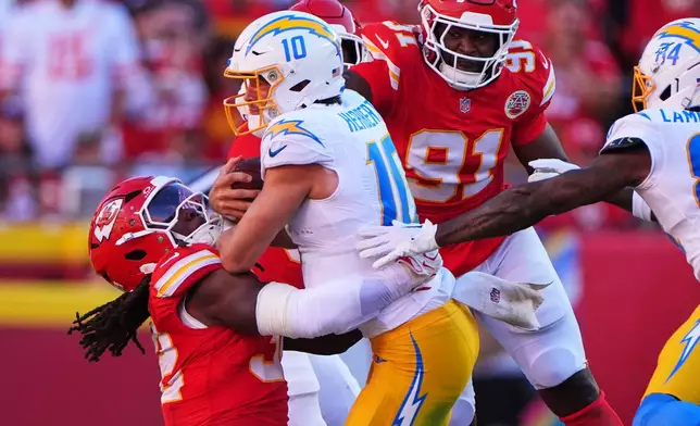 Los Angeles Chargers quarterback Justin Herbert (10) is tackled by Kansas City Chiefs linebacker Nick Bolton, left, as Herbert runs the ball during the first half of an NFL football game in Kansas City, Mo., Sunday, Oct. 18, 2026. (AP Photo/Charlie Riedel)