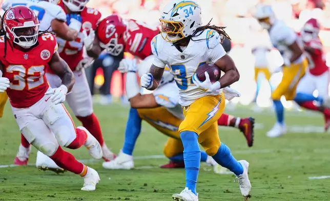 Los Angeles Chargers running back Keaton Mitchell (34) runs the ball as Kansas City Chiefs linebacker Nick Bolton (32) gives chase during the first half of an NFL football game in Kansas City, Mo., Sunday, Oct. 18, 2026. (AP Photo/Ed Zurga)