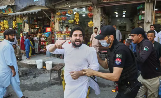Police officers detain a supporters of imprisoned former Prime Minister Imran Khan's party during a protest against the Pakistani president declared a state of emergency in northwestern Khyber Pakhtunkhwa province and suspended its government, in Peshawar, Pakistan, Monday, Oct. 12, 2026. (AP Photo/Muhammad Zubair)