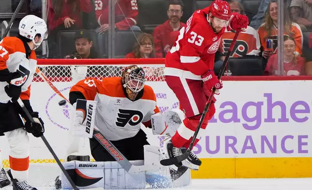 Detroit Red Wings left wing Viktor Arvidsson (33) jumps as Philadelphia Flyers goaltender Joseph Woll (53) deflects a shot in the second period of an NHL hockey game Thursday, Oct. 15, 2026, in Detroit. (AP Photo/Paul Sancya)