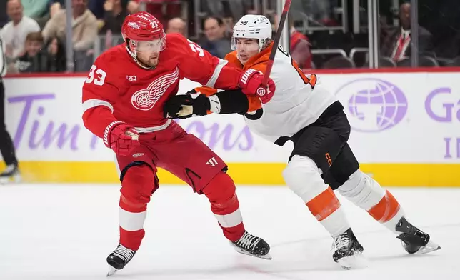 Detroit Red Wings left wing Viktor Arvidsson (33) is checked by Philadelphia Flyers defenseman Oliver Bonk (59) in the first period of an NHL hockey game Thursday, Oct. 15, 2026, in Detroit. (AP Photo/Paul Sancya)