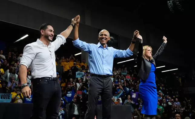 Former President Barack Obama, center, joined by Democratic nominee for U.S. Senate Abdul El-Sayed, left, and Democratic gubernatorial nominee and Michigan Secretary of State Jocelyn Benson raise hands during a campaign event at Cass Technical High School Saturday, Oct. 24, 2026, in Detroit.(AP Photo/Paul Sancya)