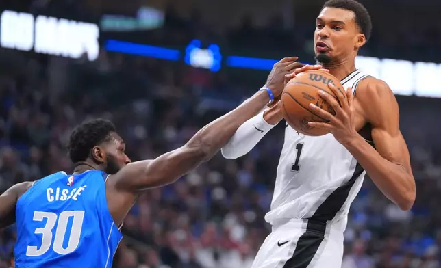San Antonio Spurs forward Victor Wembanyama, right, tries to control the ball after a rebound as Dallas Mavericks center Moussa Cisse tries to disrupt him during the first half of an NBA basketball game Saturday, Oct. 24, 2026, in Dallas. (AP Photo/Julio Cortez)