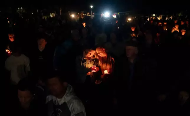 People mourn during a candlelight vigil at Drake Park following a deadly shooting at Silver Rail Elementary School in Bend, Ore. on Thursday, Oct. 15, 2026. (Eli Imadali/Oregon Public Broadcasting via AP)