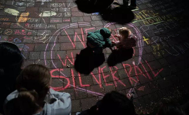Children draw with chalk during a candlelight vigil at Drake Park following a deadly shooting at Silver Rail Elementary School in Bend, Ore. on Thursday, Oct. 15, 2026. (Eli Imadali/Oregon Public Broadcasting via AP)