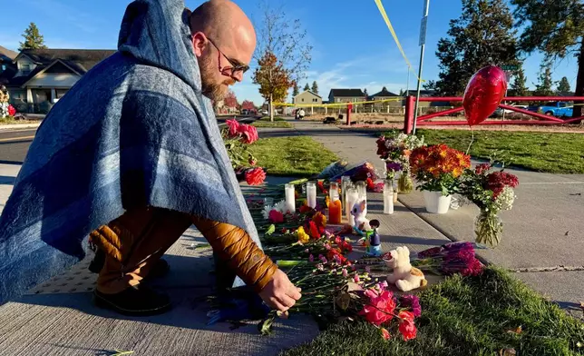 A person places flowers at a makeshift memorial on the other side of Silver Rail Elementary School in Bend, Ore., on Friday, Oct. 16, 2026, a day after a deadly shooting. (AP Photo/Haven Daley)