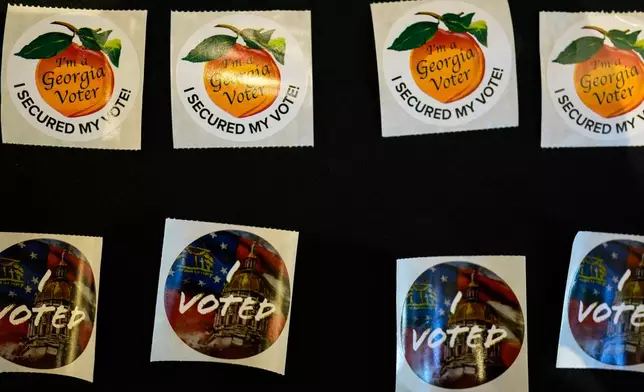 Stickers are seen at The High Museum of Art voting center on the first day for early voting in Georgia, Tuesday, Oct. 13, 2026, in Atlanta. (AP Photo/Mike Stewart)