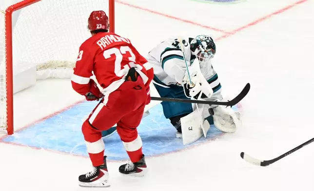 San Jose Sharks goaltender Alex Nedeljkovic, right, blocks a shot attempt from Detroit Red Wings left wing Lucas Raymond during the first period of an NHL hockey game, Saturday, Oct. 17, 2026, in Detroit. (AP Photo/Jose Juarez)